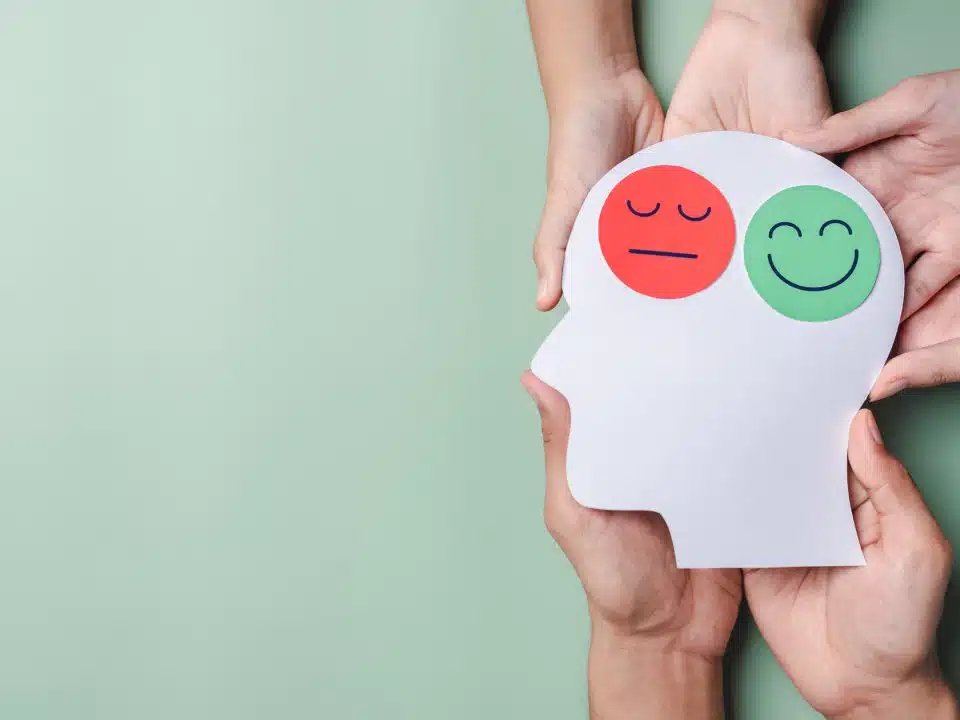 Hands holding sad face and happy smiley face on brain paper cut out, bipolar and depression, mental health concept, personality, mood change, therapy healing split concept